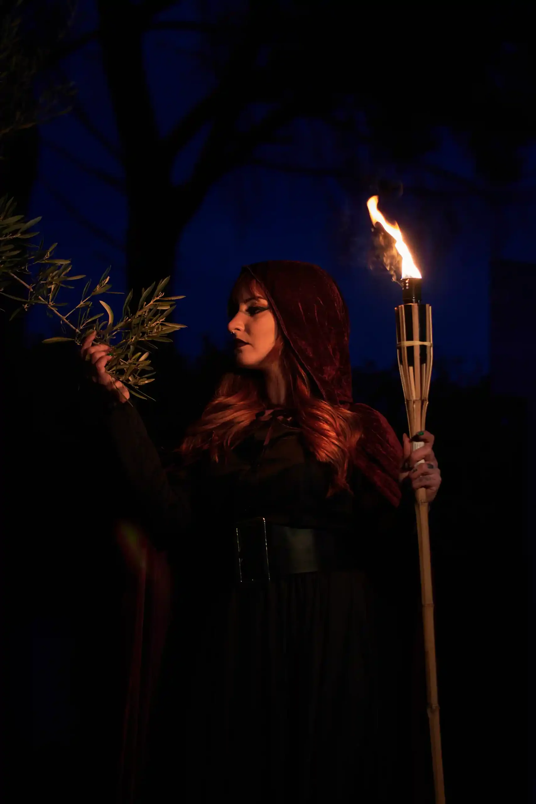 woman disguised as a witch holding a flaming torch during halloween night
